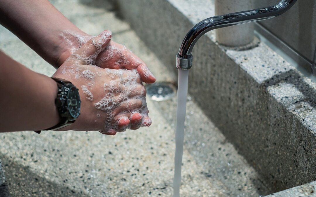 Close up of hand washing with water running and soap suds on hands.