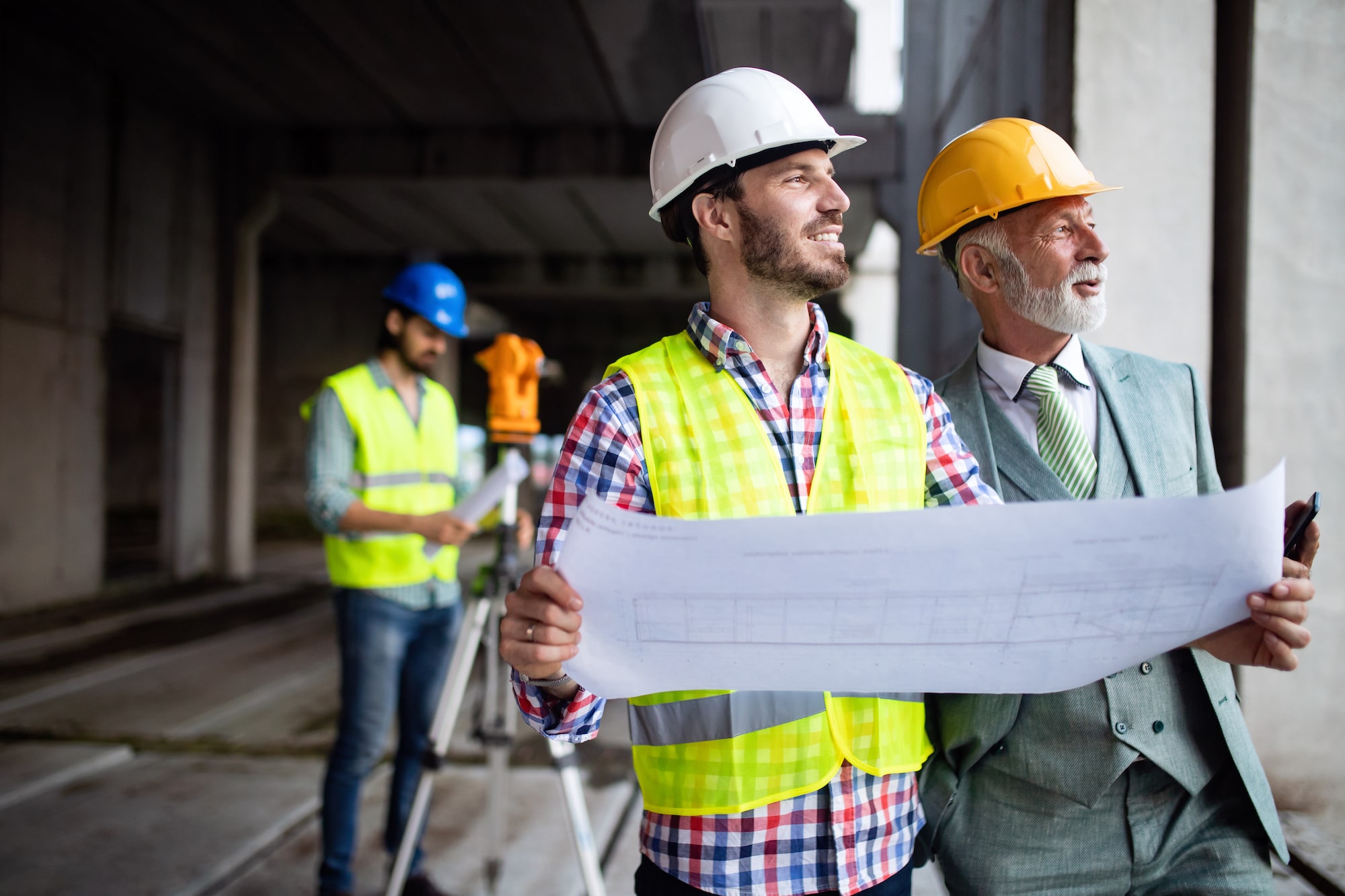 Engineer, foreman and worker discussing and working in building construction site