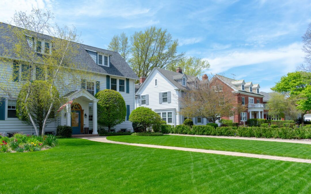 Lush green yards sprawl in front of beautiffuly maintained homes in a suburb.