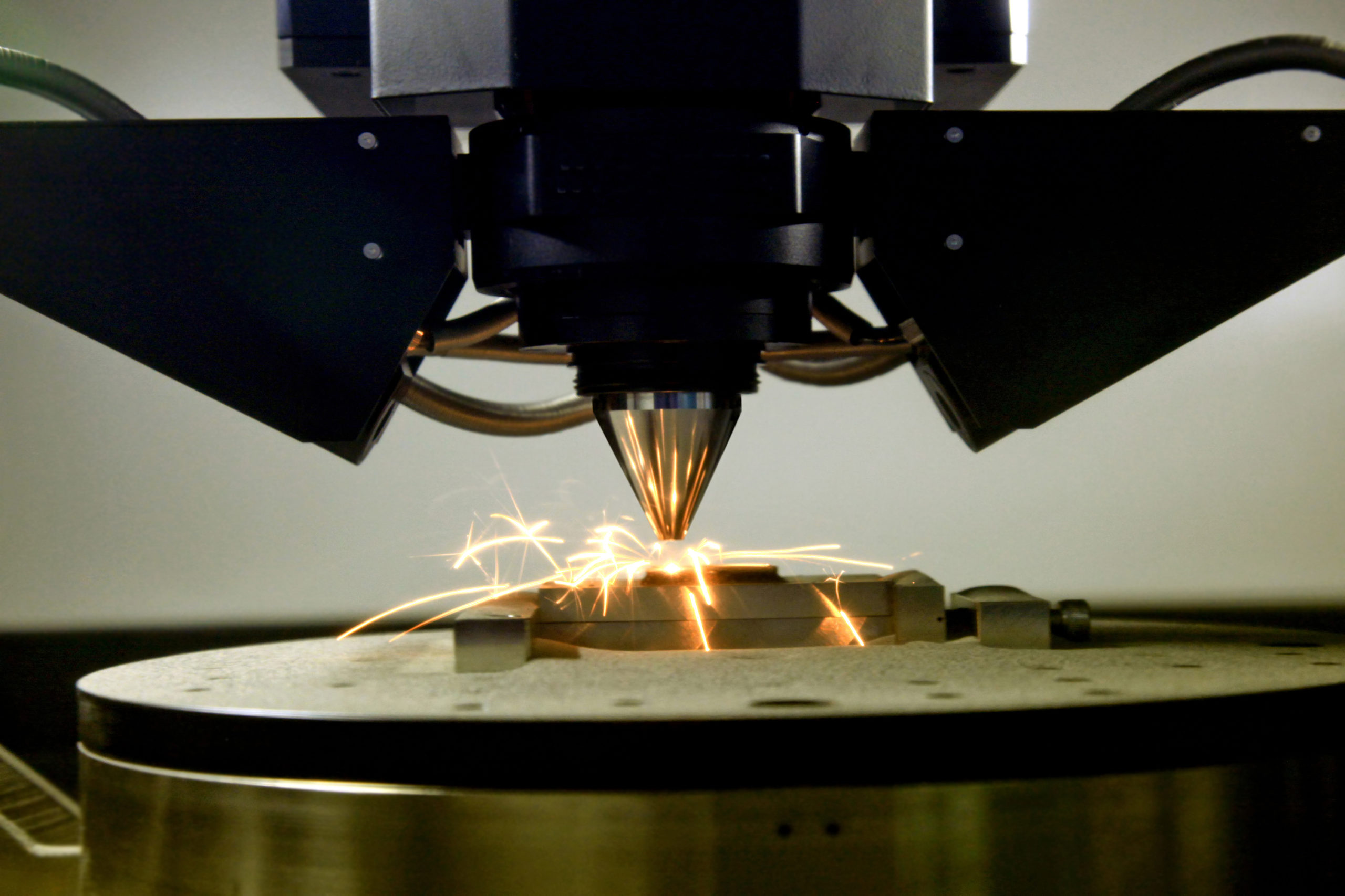 close-up of sparks flying off a 3D printer as it prints metal.